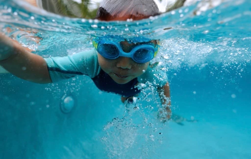 A happy swimmer underwater in the pool during a lesson